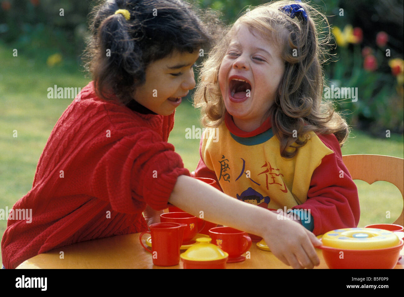 zwei Mädchen spielen mit Tee-Set im Garten Stockfoto