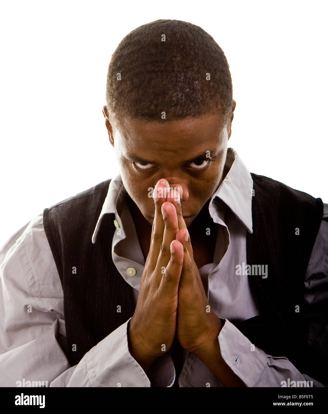 Ein junger schwarzer Mann gekleidet in grau und schwarz beten und Blick in die Kamera Stockfoto