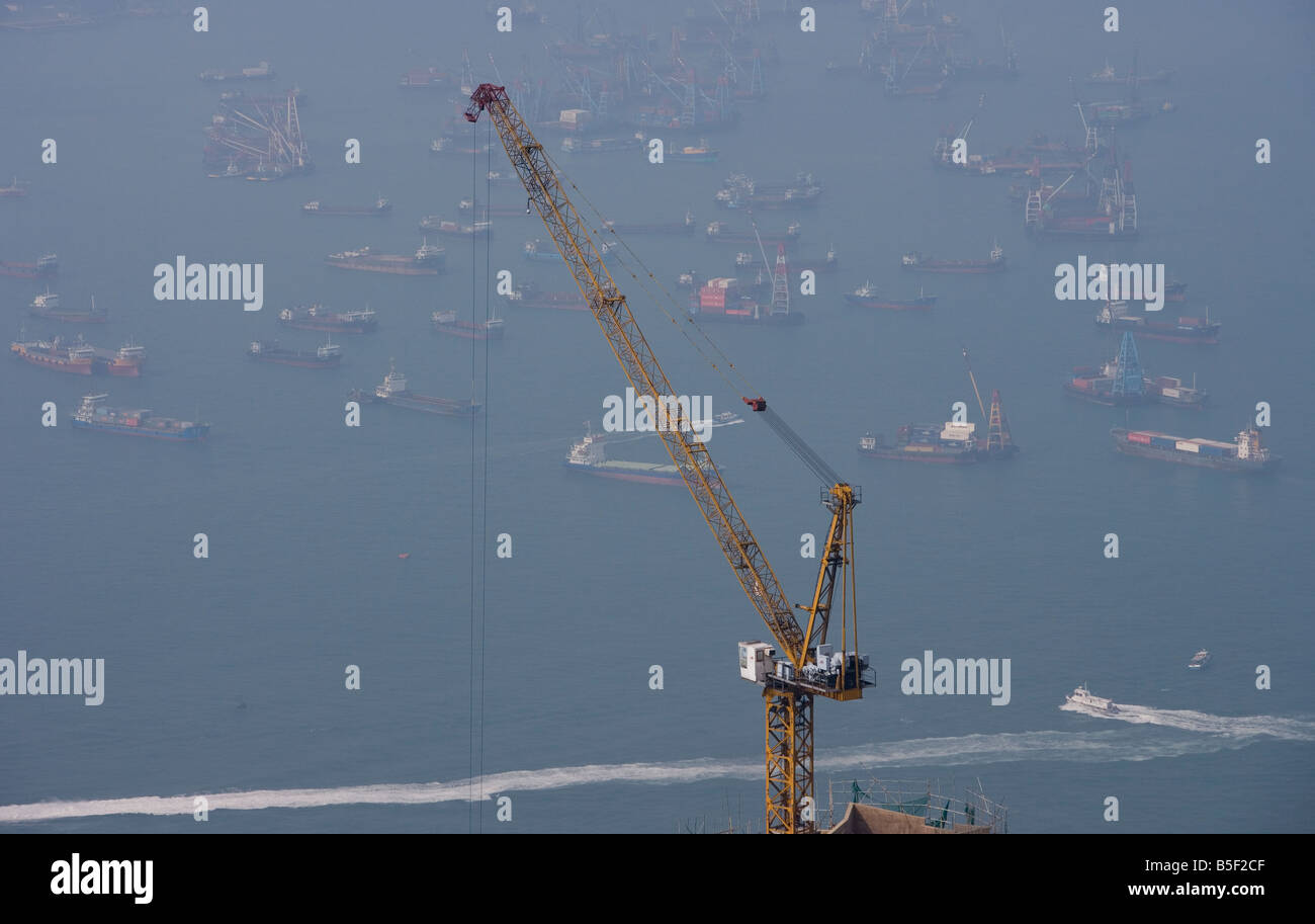 Ein Baukran überragt Containerschiffe im Hafen von Hong Kong. Stockfoto