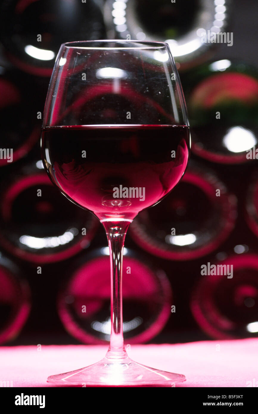 ein Glas Rotwein vor Flaschen Stockfoto