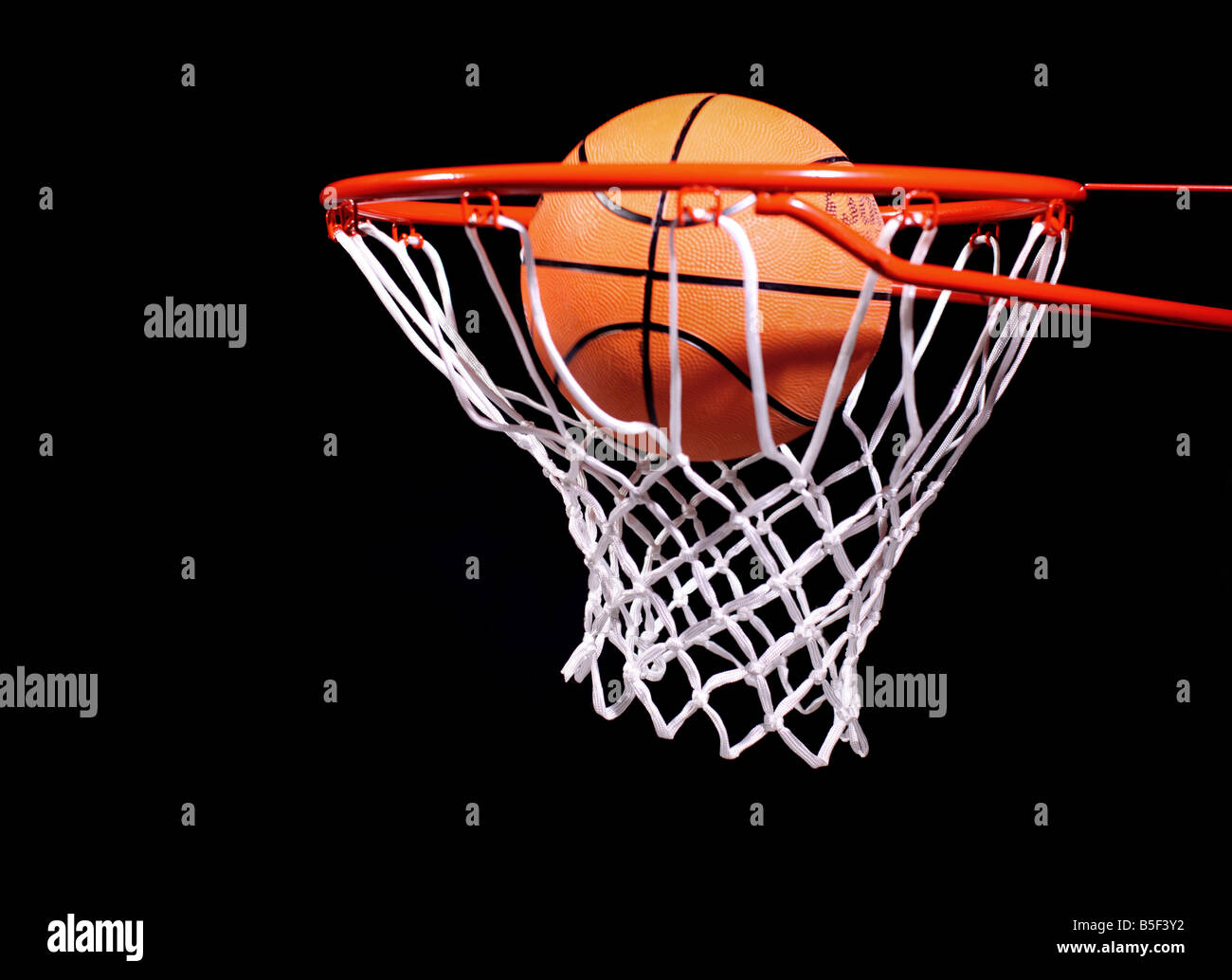Basketball in Reifen auf schwarzen Hintergrund Stockfoto