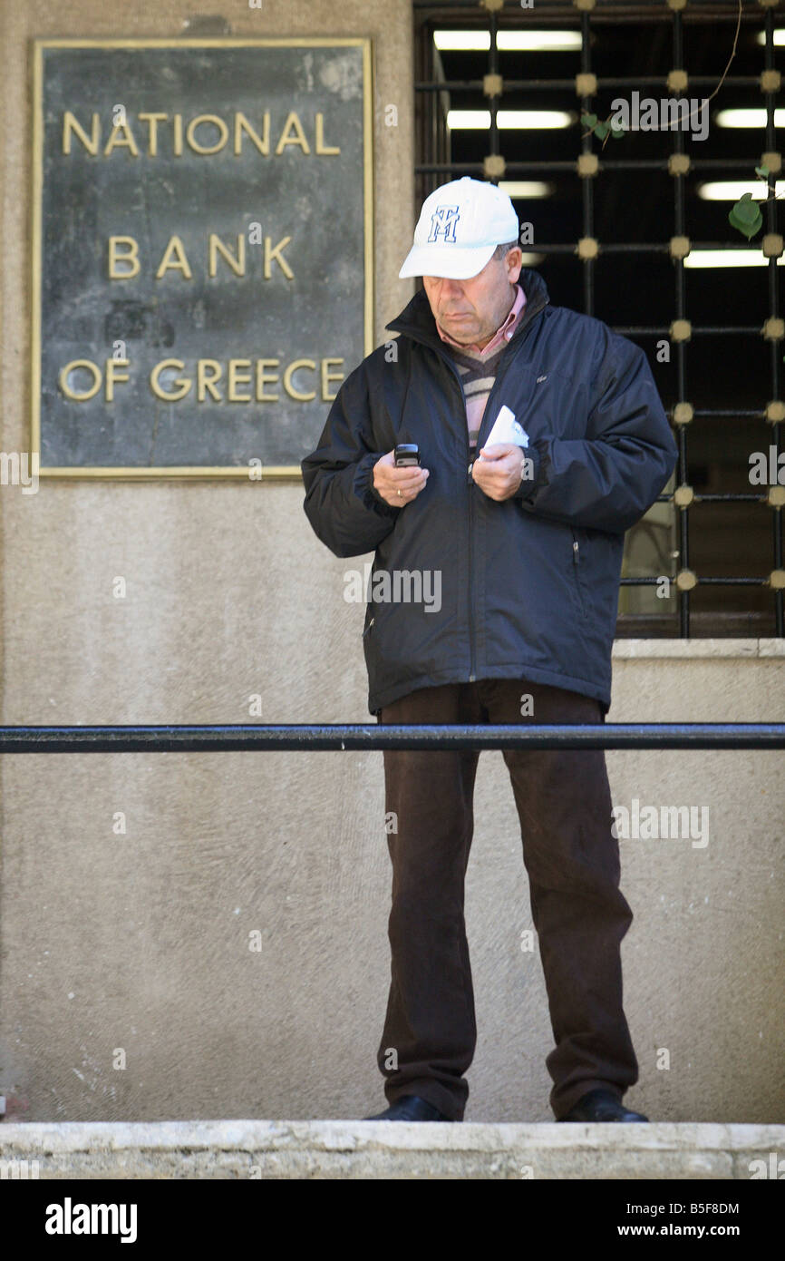 Mann vor eine Filiale der National Bank of Greece in Rhodos, Griechenland Stockfoto