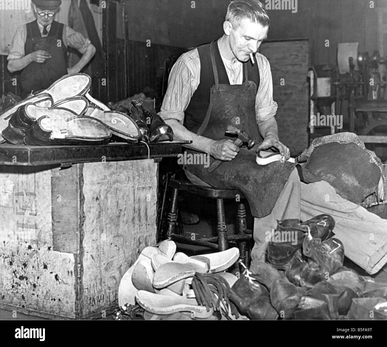 Clogs, die wertvolle Leder sparen kehren unter Arbeitern in schweren Wqr Branchen hier begünstigen ein Clog-Maker bei der Arbeit am ist Stockfoto