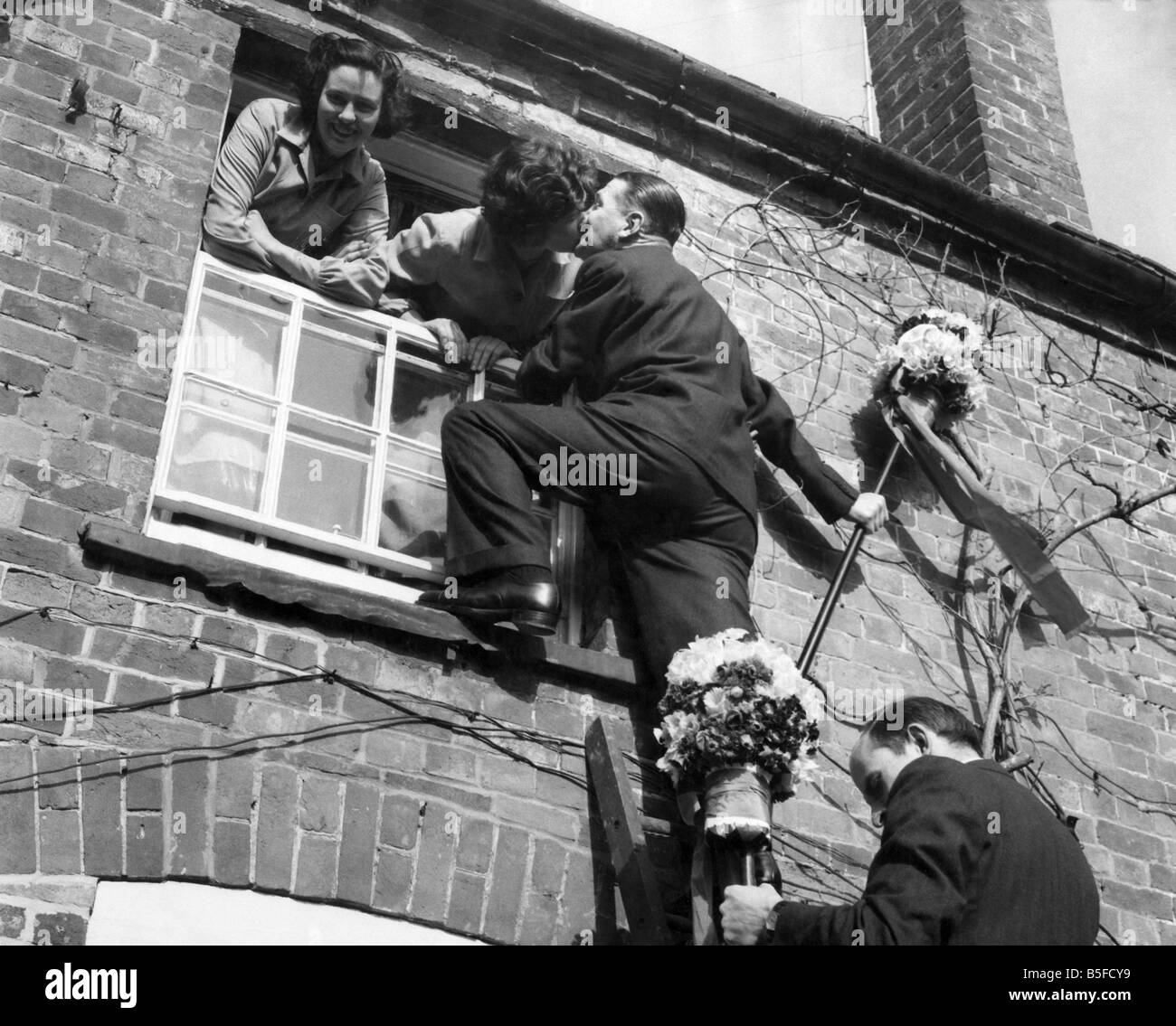 Tutti-Männer besteigen eine Leiter zu dem traditionellen Kuss das Fenster während der Hock-Flut-Festival in Hungerford. April 1955 P029159 Stockfoto