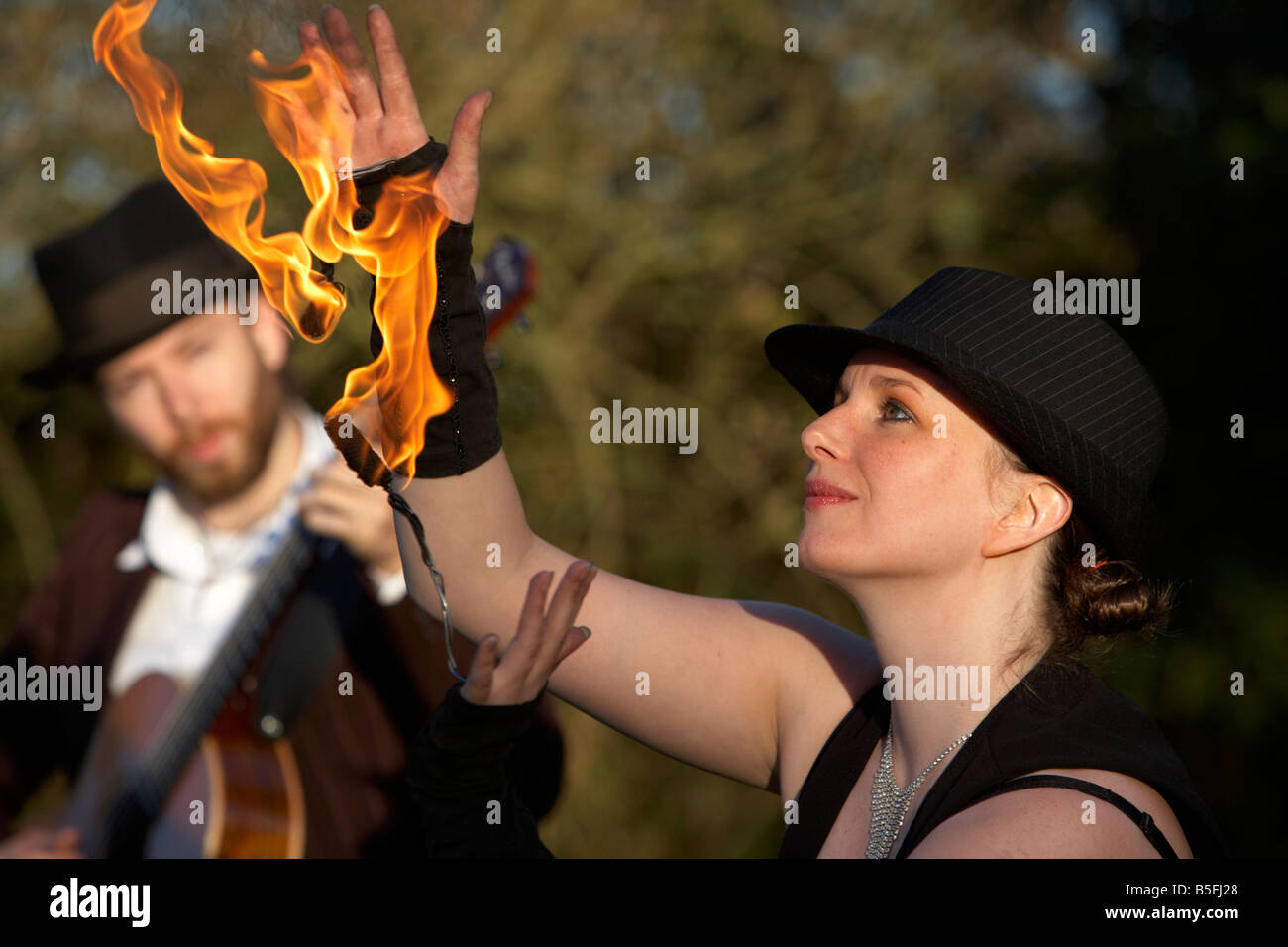 Mann, die Gitarre mit Firepoise Frau Feuer Tänzerin Spiel mit dem Feuer spielen Stockfoto