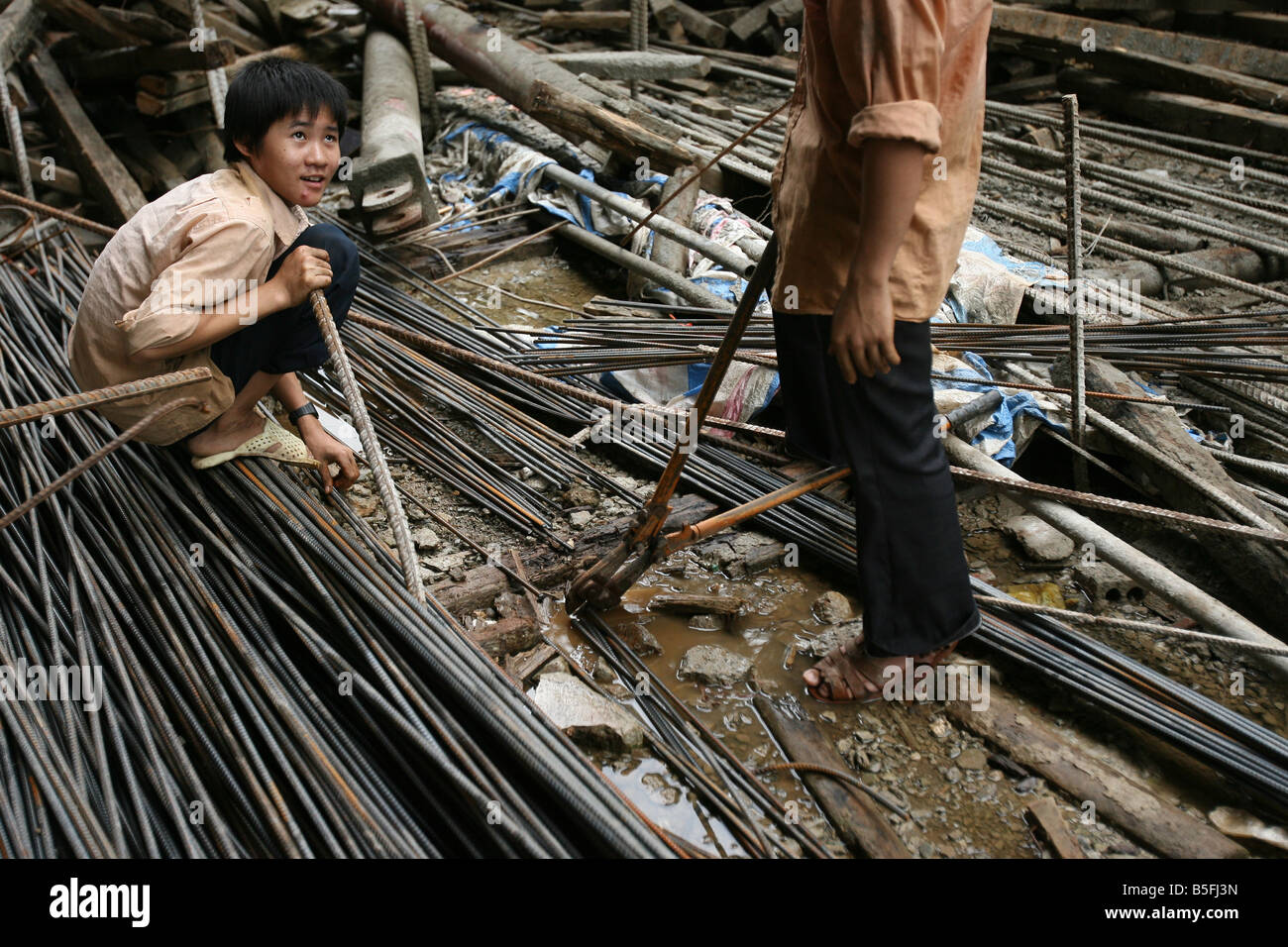 Ein kleiner Junge sitzt auf Stahlstangen auf einer Baustelle in Hanoi, Vietnam Stockfoto