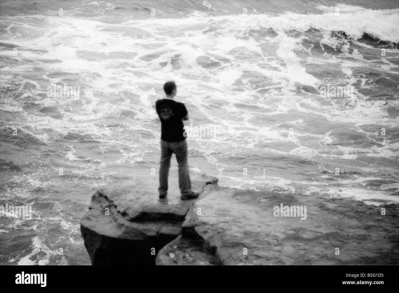 Mann steht auf dem felsigen Ufer La Jolla Anzeigen von den Wellen des Ozeans unten. Stockfoto