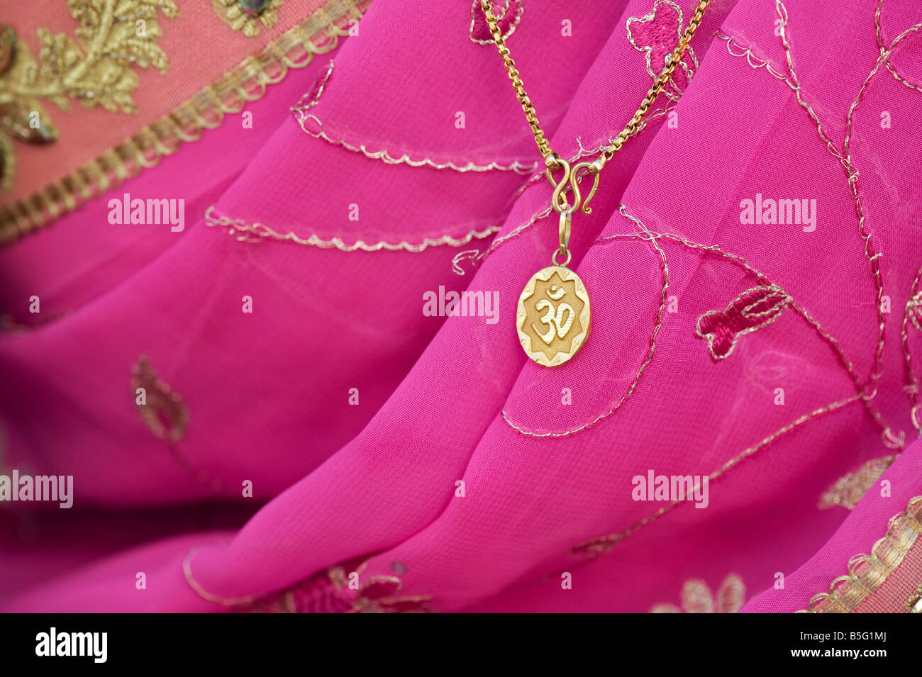 OM Pendent auf rosa Sari getragen von einem indischen Mädchen Stockfoto