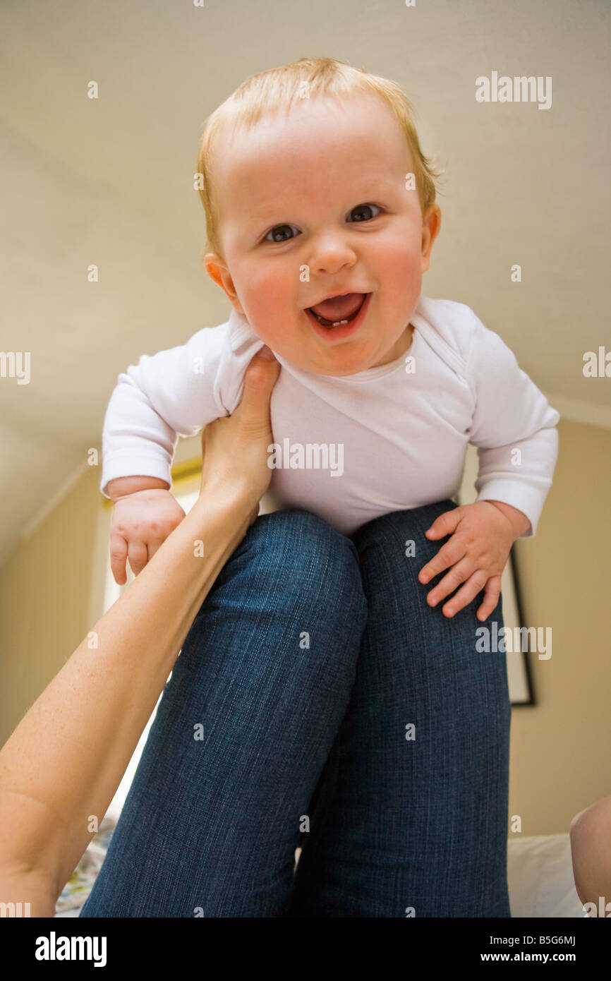 Ein 10 Monate altes Baby Boy ausgewogen auf die Knie Mütter aus seiner Perspektive der Mütter Stockfoto