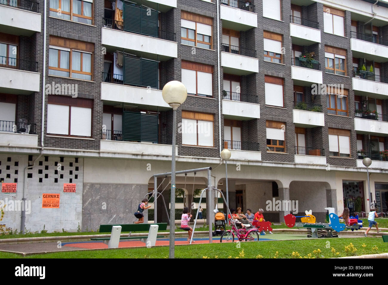 Kinder benutzen Spielgeräte vor einer Wohnung Wohneinheit in Guernica Nordspanien Stockfoto