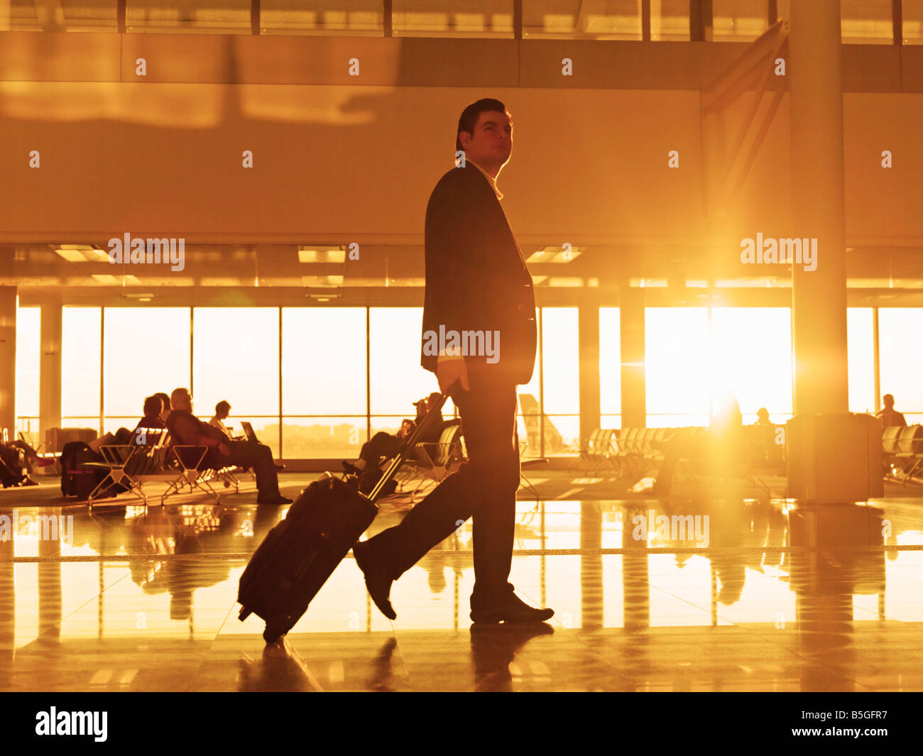 Reisende mit Gepäck zu Fuß die Flughafen-Halle bei Sonnenaufgang Stockfoto