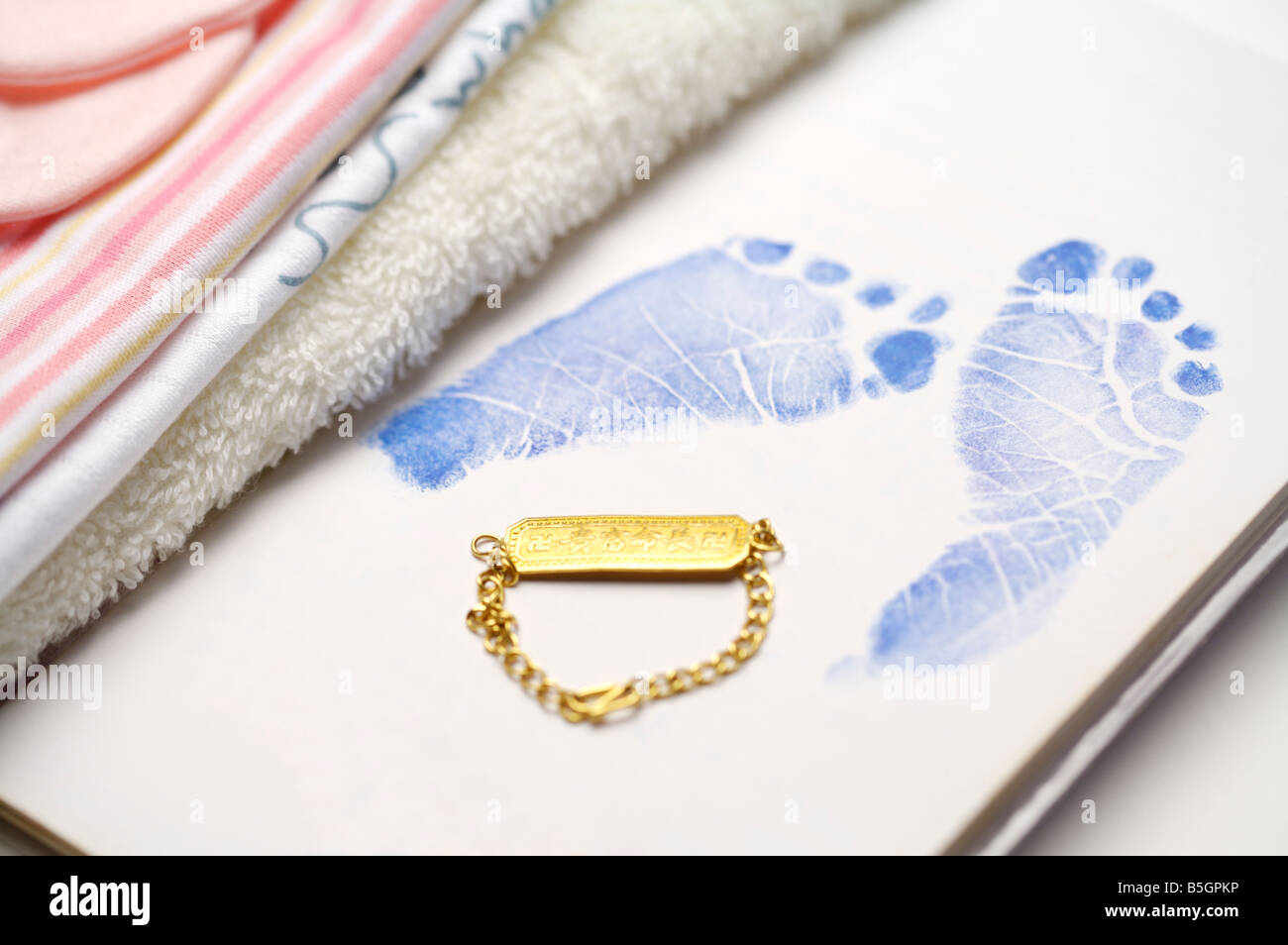 Gold Glücksbringer neben einem Baby Fußabdruck Stockfoto
