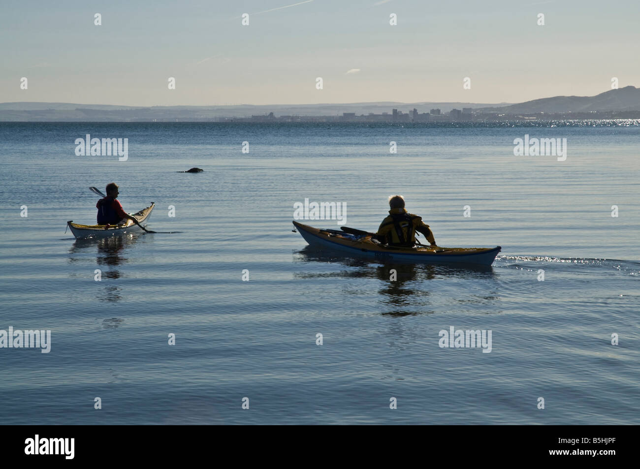dh Kayak Küste Kanu WASSERSPORT KAJAKFAHREN FIFE SCHOTTLAND zwei Frauen Kanufahrer paddeln Boot auf See 2 UK Mädchen Paar Kajaks Stockfoto