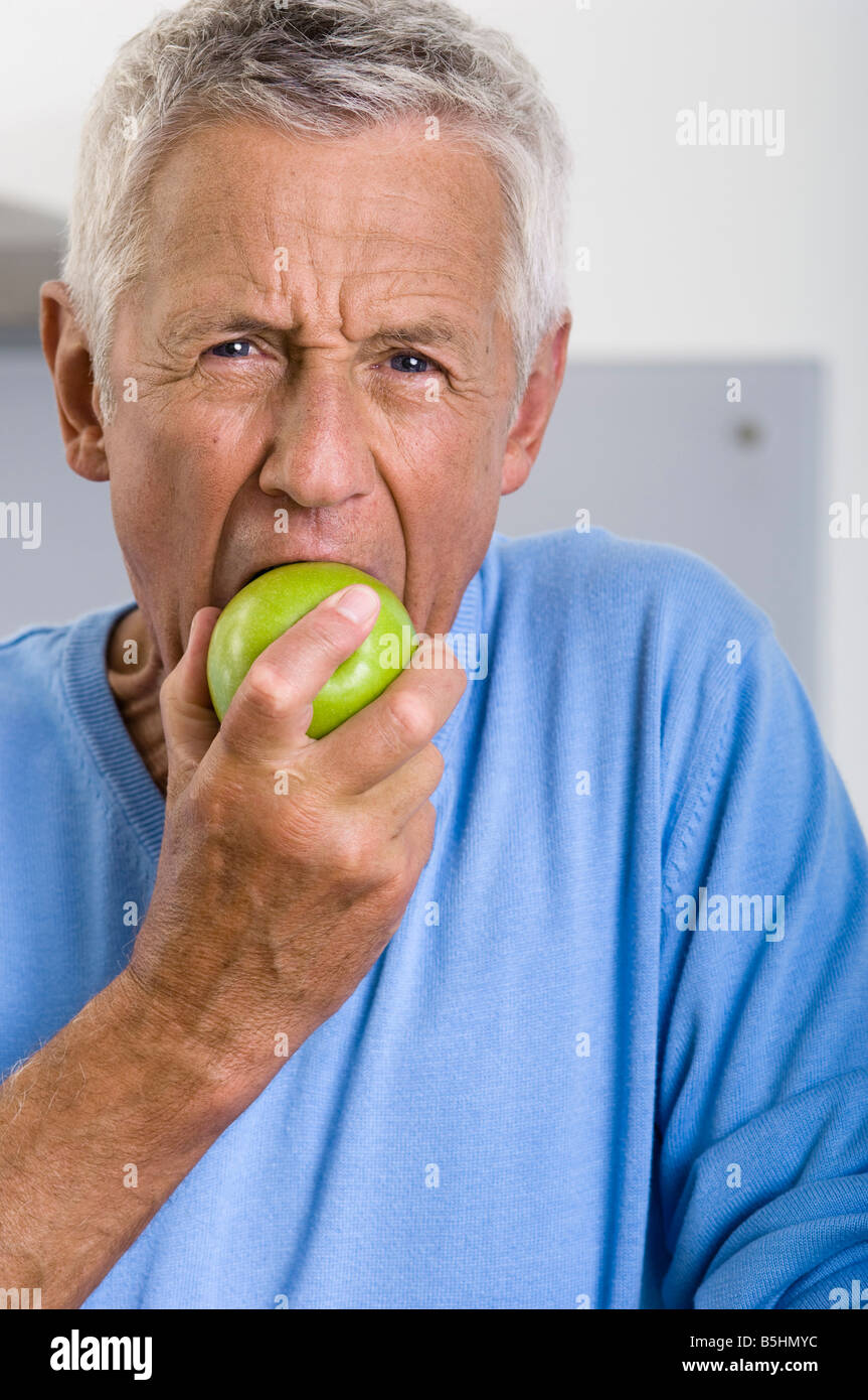 Ältere Mann isst einen Apfel Stockfoto
