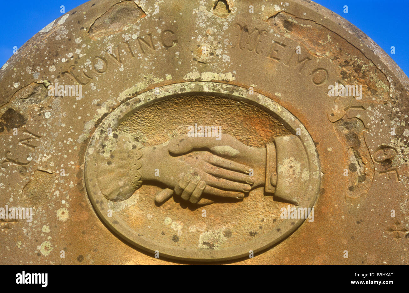 Grabstein unter blauem Himmel mit geschnitzten männliche Hand auszustrecken und halten oder schütteln weibliche hand In stillem Gedenken Stockfoto