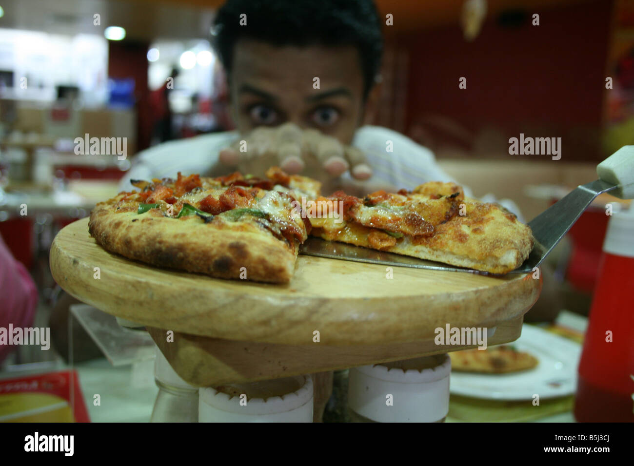 Junge indische Männer warten darauf, seine Pizza zu verschlingen, befahl er Stockfoto