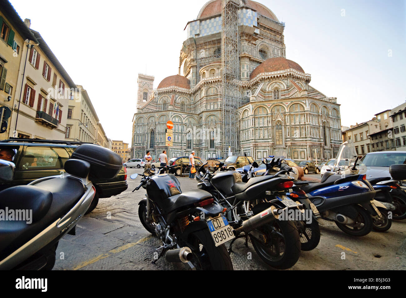 FLORENZ, Italien – Ein Meer von Motorrollern und Motorrädern säumt eine enge Straße im historischen Zentrum von Florenz. Die dicht gepackten Reihen von geparkten Vespas und anderen Motorini zeigen einen typischen Aspekt des modernen italienischen städtischen Lebens vor dem Hintergrund jahrhundertealter Architektur. Stockfoto