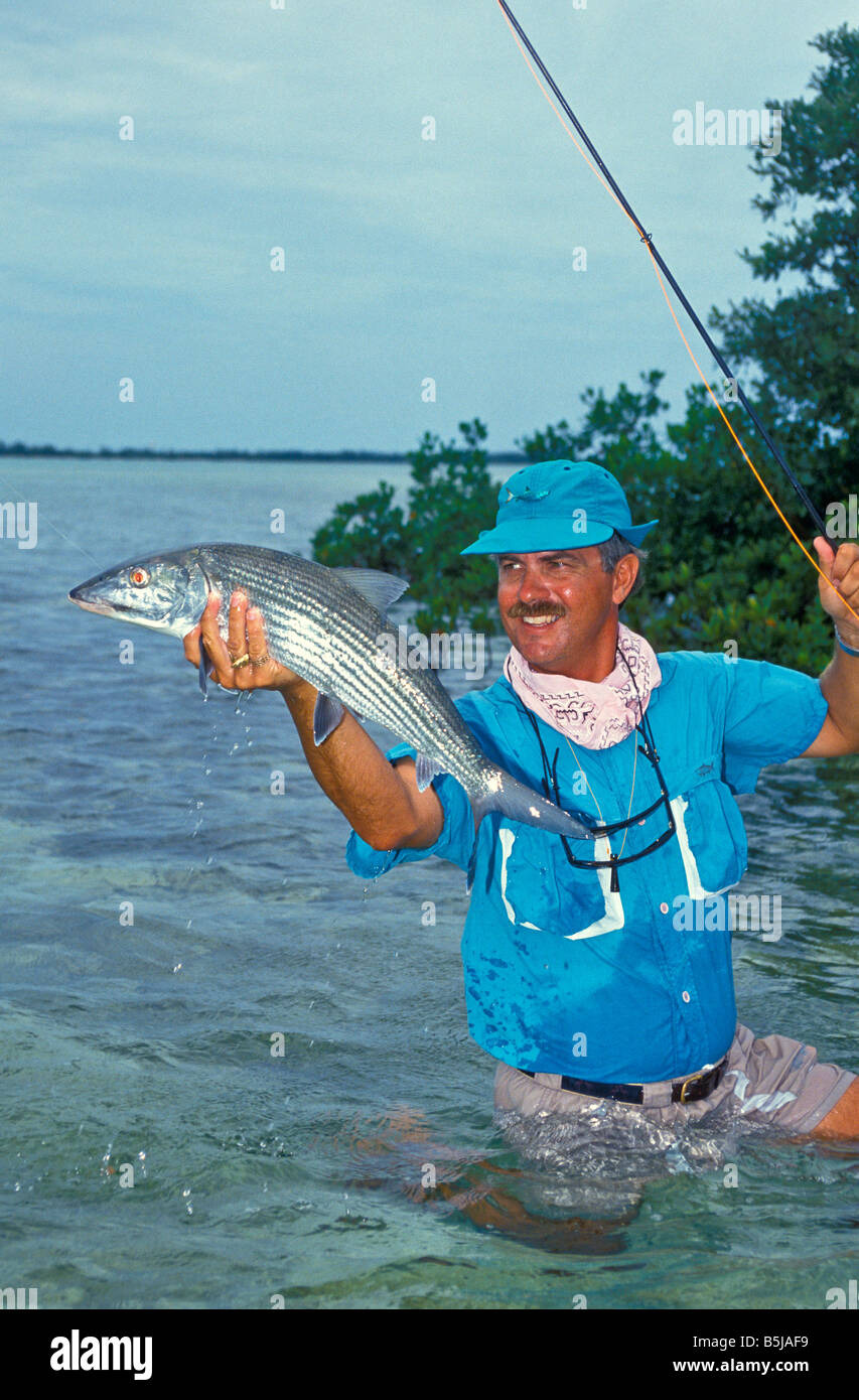stolz auf männliche Angler hält 9lb Trophäe Bonefish waten im seichten Wasser Bahamas Insel Andros Stockfoto