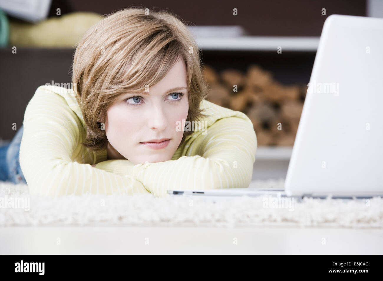 Porträt der jungen Frau liegt auf Boden zu Hause vor Laptop-computer Stockfoto