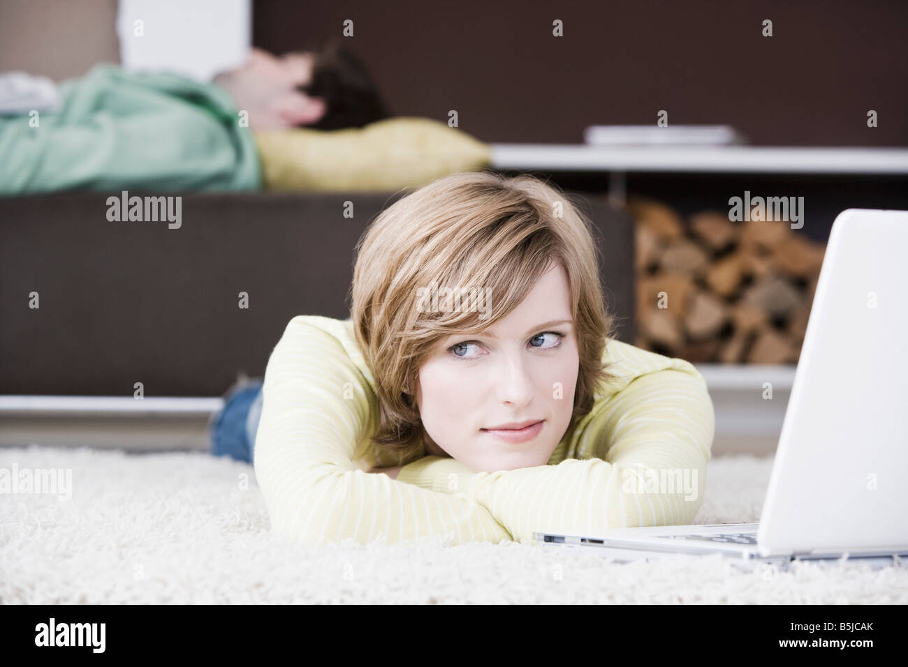Porträt der jungen Frau liegt auf Boden zu Hause vor Laptop-computer Stockfoto
