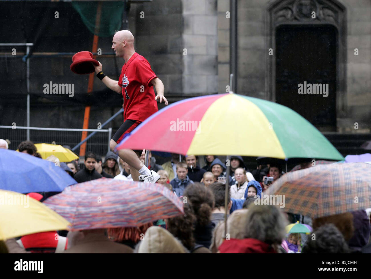 Straßenkünstler auf dem Edinburgh Fringe Festival der Royal Mile entfernt, Einradfahrer Durchführung im Regen Stockfoto