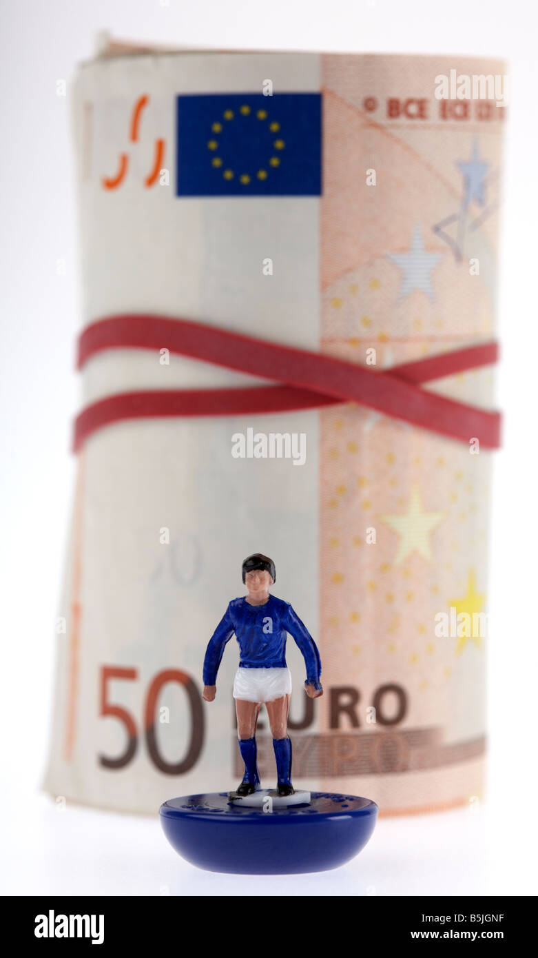 Bündel von 50 Euro-Banknoten Bargeld gefesselt in einer Rolle mit Gummiband hinter Spielzeug Fußballer Stockfoto