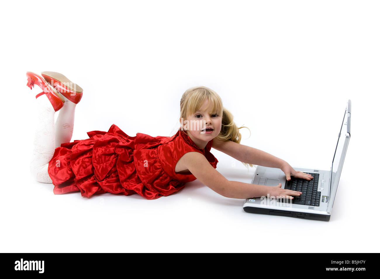 Kind im roten Kleid spielen oder Laptop Computergerät. Stockfoto