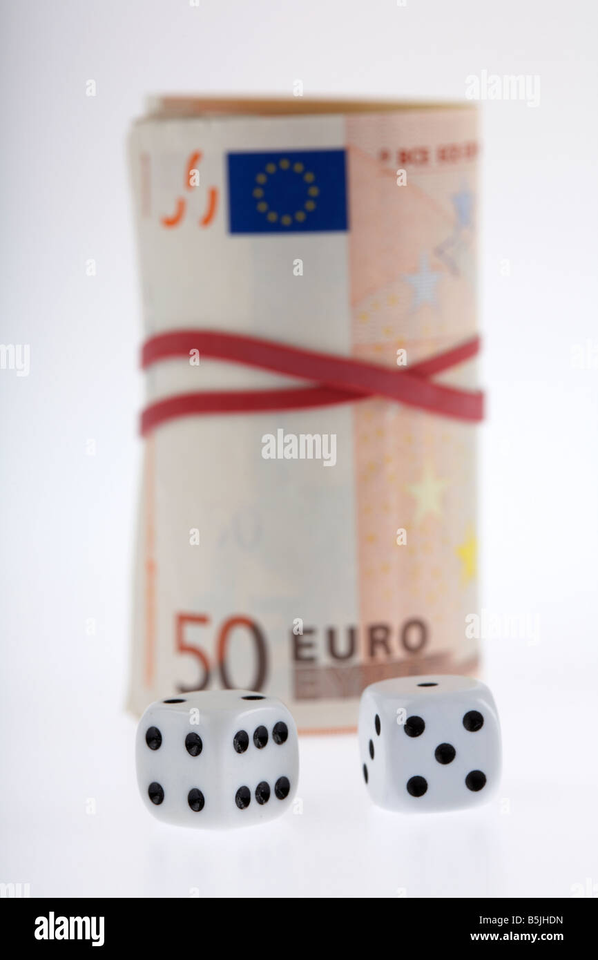 zwei Würfel vor Bündel 50 Euro Banknoten Geldscheine gefesselt in einer Rolle mit Gummizug Stockfoto