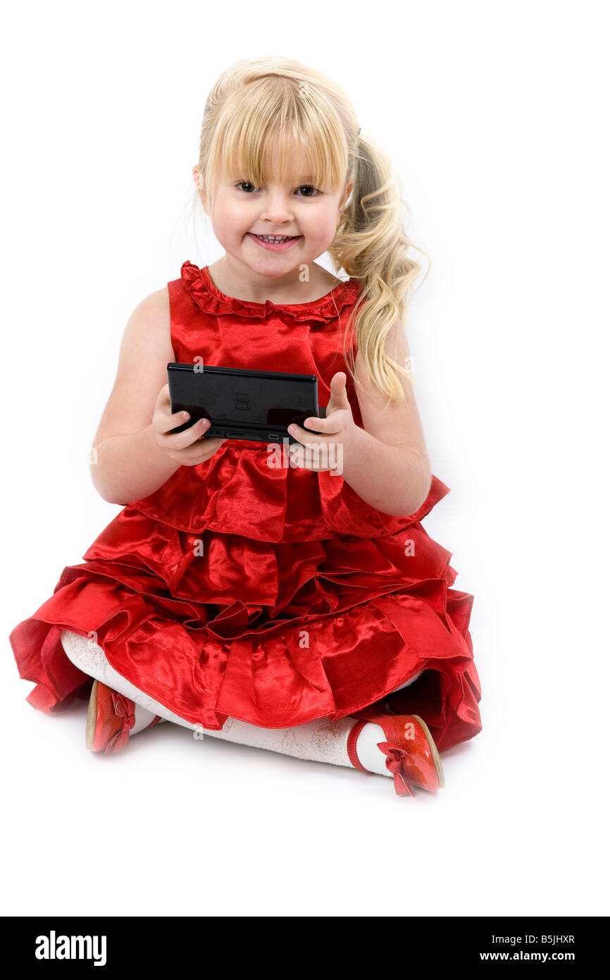 Kind im roten Kleid spielen oder Laptop Computergerät. Nintendo DS Lite Stockfoto