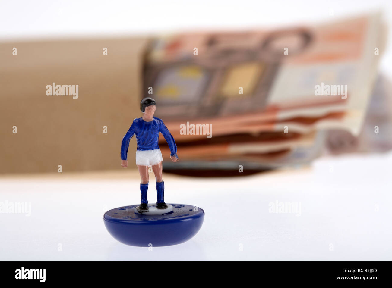 Bündel von 50 Euro-Banknoten-Bargeld in einem braunen Papierumschlag hinter Spielzeug Fußballer Stockfoto