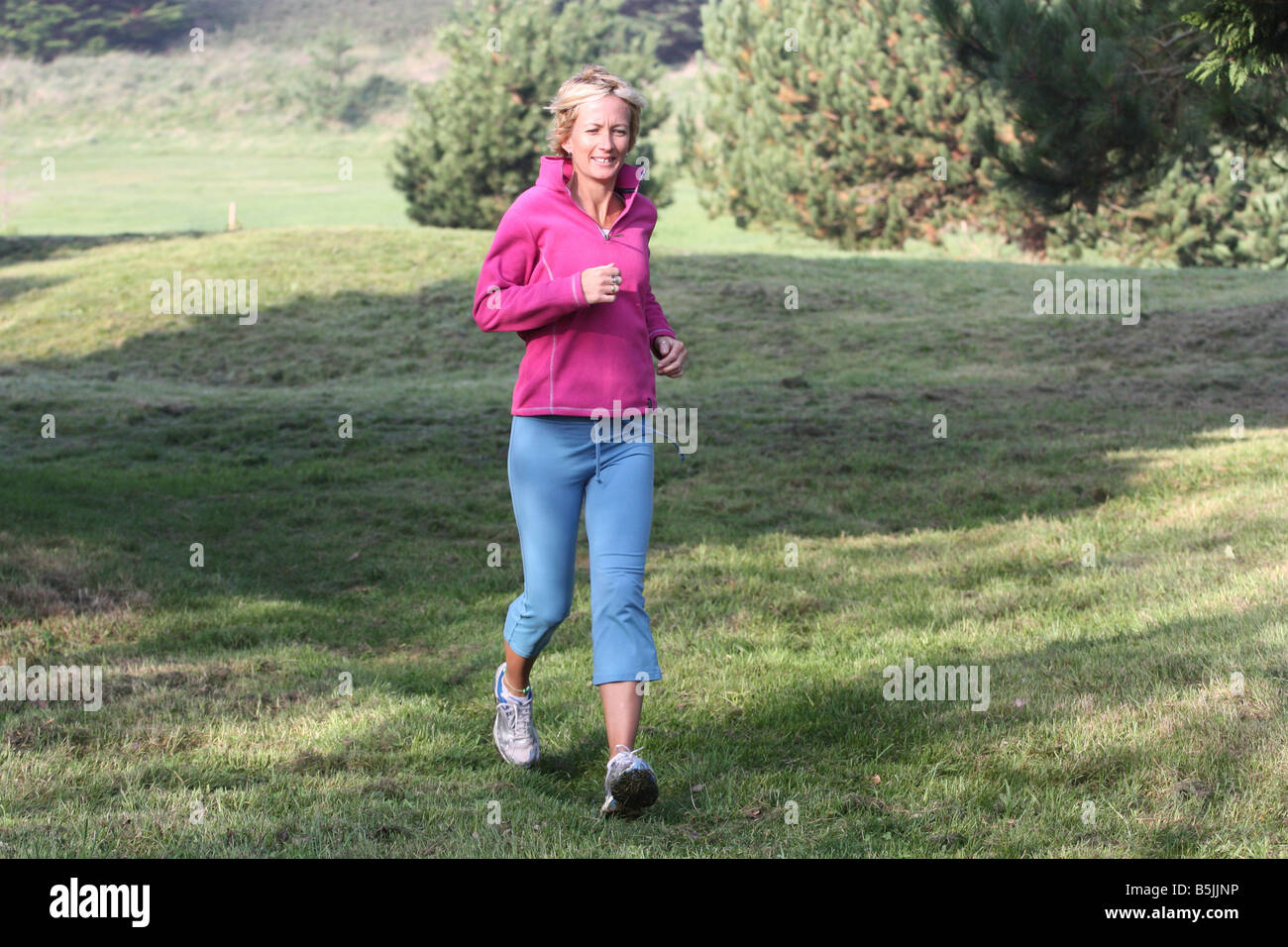 Junge blonde Frau im Freien. Joggen in der Landschaft. Stockfoto
