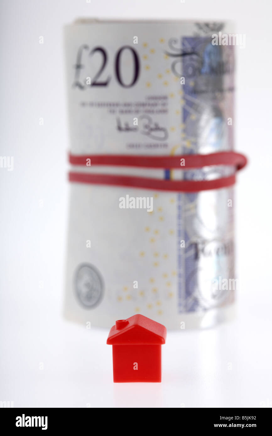 ein rotes Haus auf ein Bündel von 20 Pfund Sterling Banknoten Bargeld gefesselt in einer Rolle mit Gummizug Stockfoto