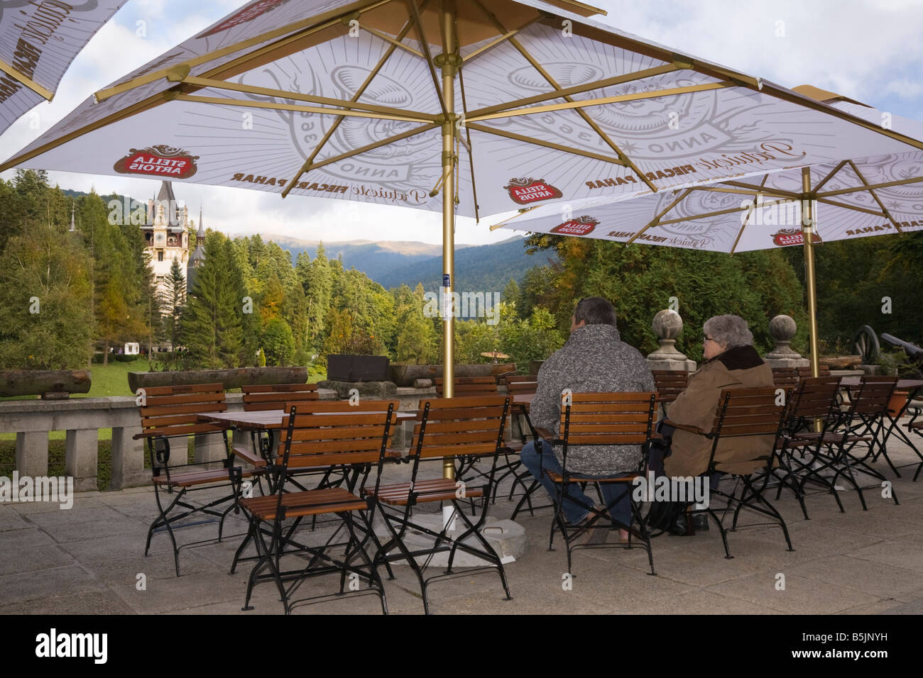 Sinaia Prahova Siebenbürgen Rumänien Leute sitzen unter Sonnenschirm im Café im Freien mit Blick auf Schloss Peles Gelände Stockfoto