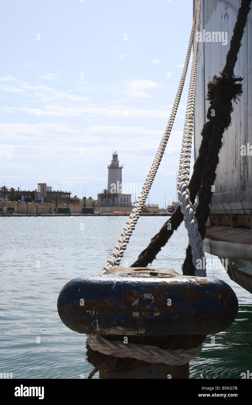 Malaga Costa del Sol Spanien Festmacher Poller mit Schiffs-Seil gebunden um ihn herum Malaga Leuchtturm im Hintergrund Stockfoto