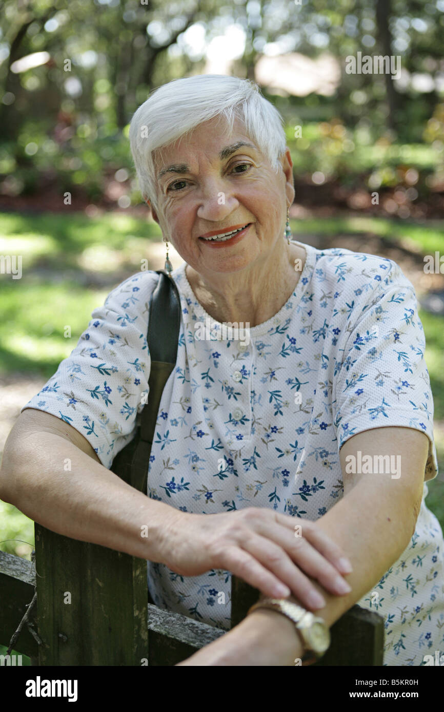 Ein ziemlich silbernen Haaren in ihrem 80er Jahre stützte sich auf einen Zaun im park Stockfoto