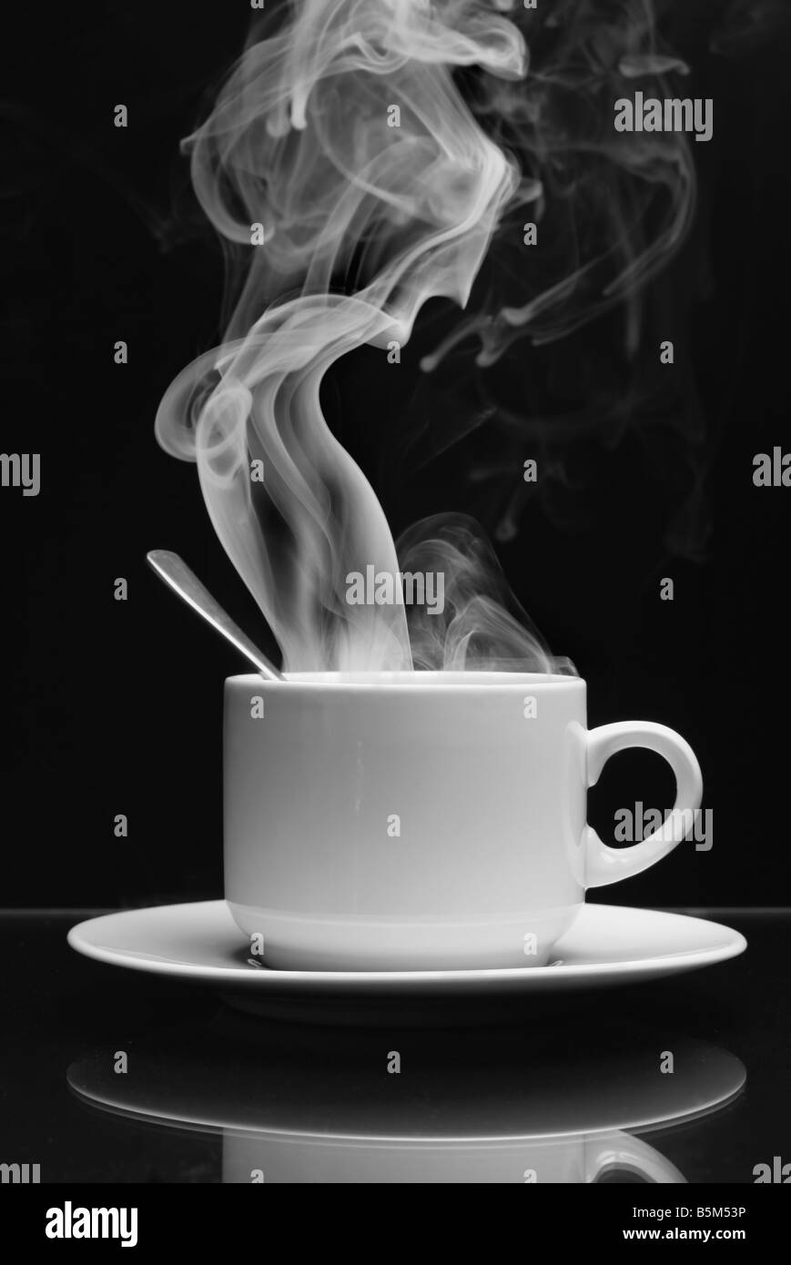 Tasse Heißgetränk mit Dampf auf schwarzem Hintergrund Stockfoto