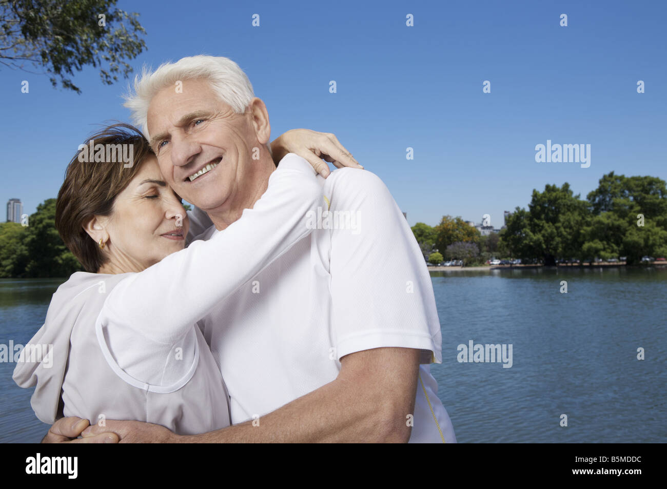 Ein älteres Paar an einem See umarmt Stockfoto