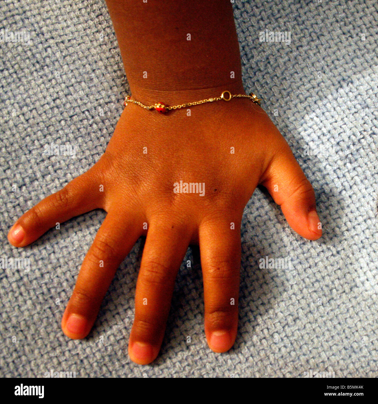 Kind Hand dunkle Haut mit ein Goldarmband Stockfoto