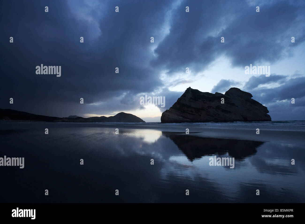 Nähert sich Sturm & Torbogen Inseln spiegelt sich in feuchten Sand der Wharariki Beach bei Abenddämmerung Cape Farewell Nelson Region New Zealand Stockfoto