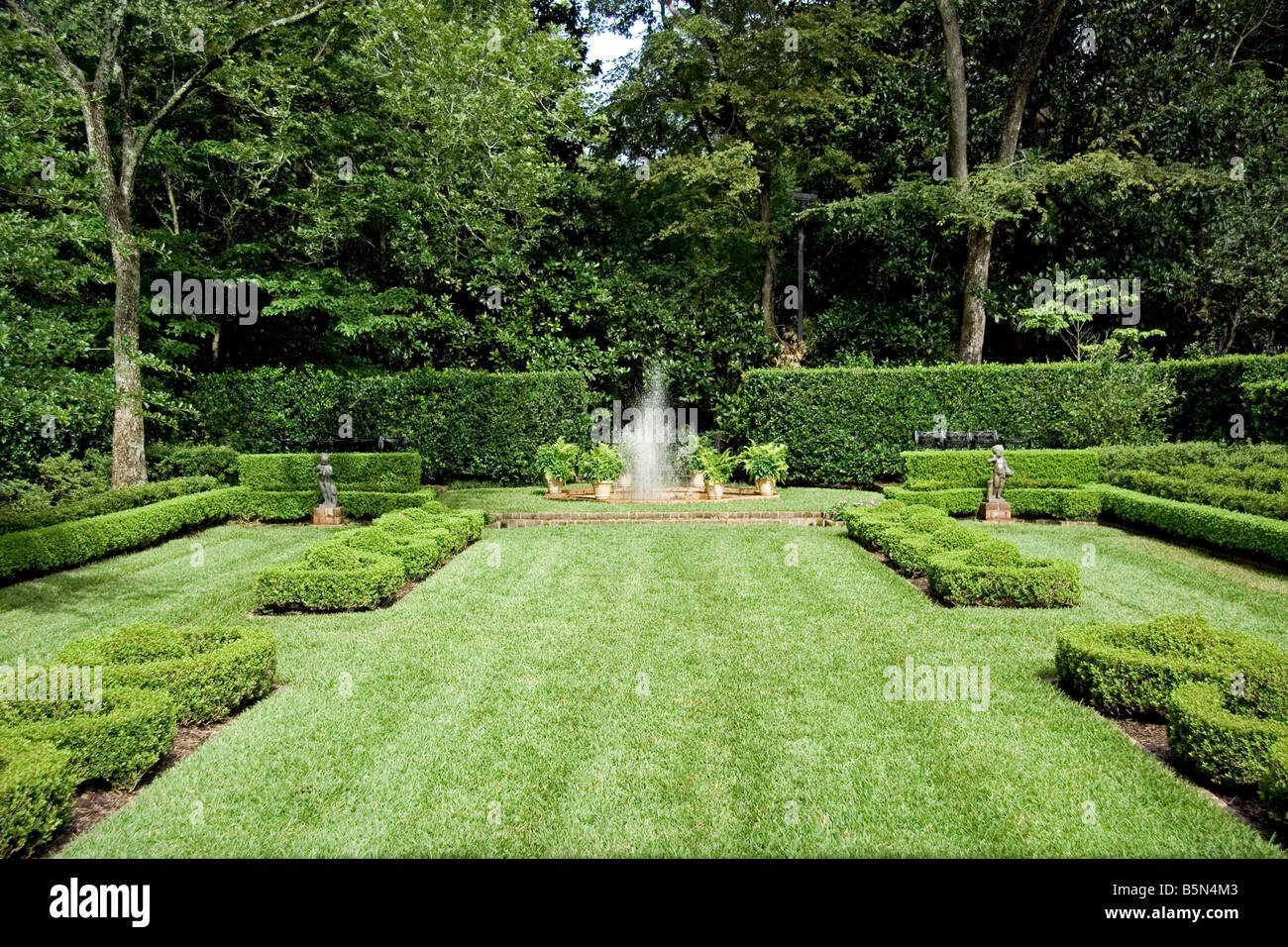 Ein englischer Garten mit einem Brunnen in der Mitte Spritzen Stockfoto