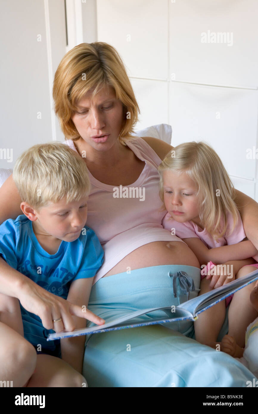 Schwangere Mutter liest ein Buch zu ihrem Sohn und Tochter Stockfoto