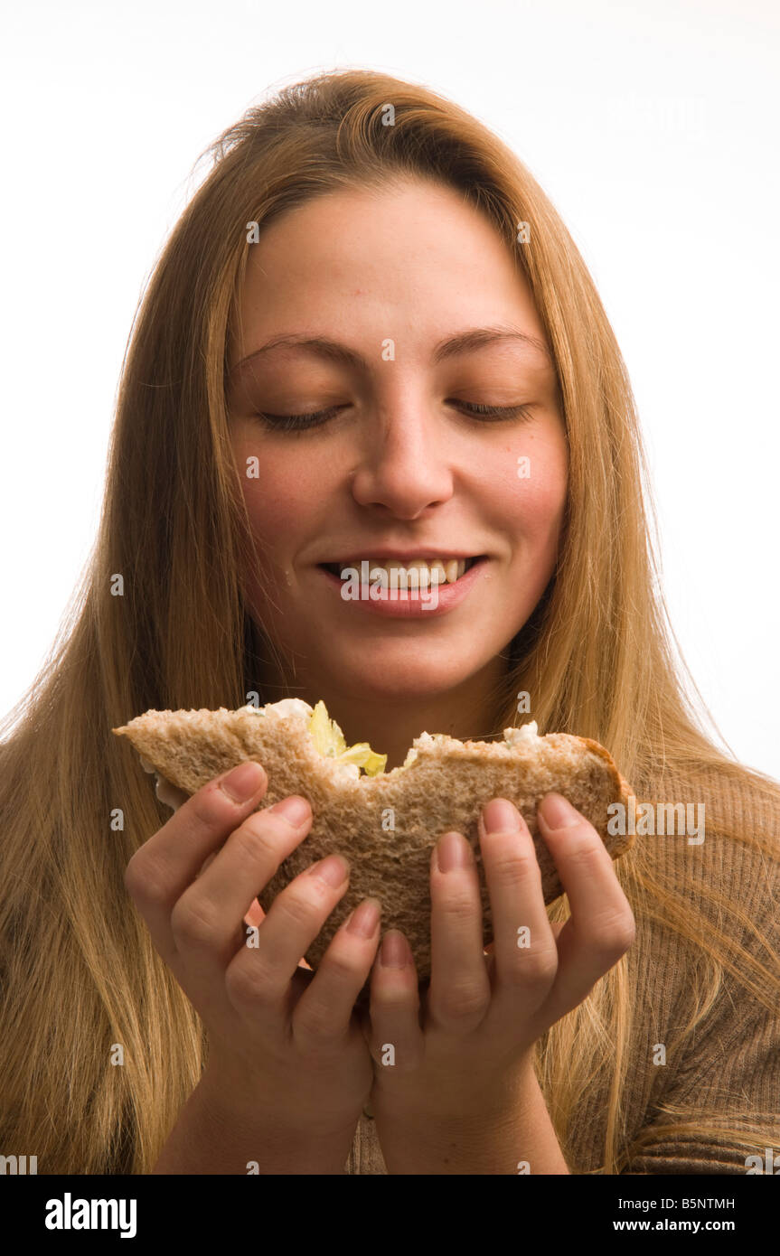 Junge blonde Frau auf einer Diät essen einen gesundes Schwarzbrot-Hähnchen-Salat-sandwich Stockfoto