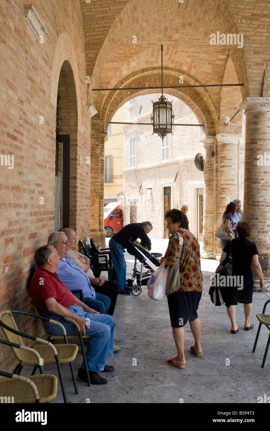 alte Männer die Zeit unter den Bögen des Palazzo Comunale - Rathaus - von Offida in Le Marche Stockfoto