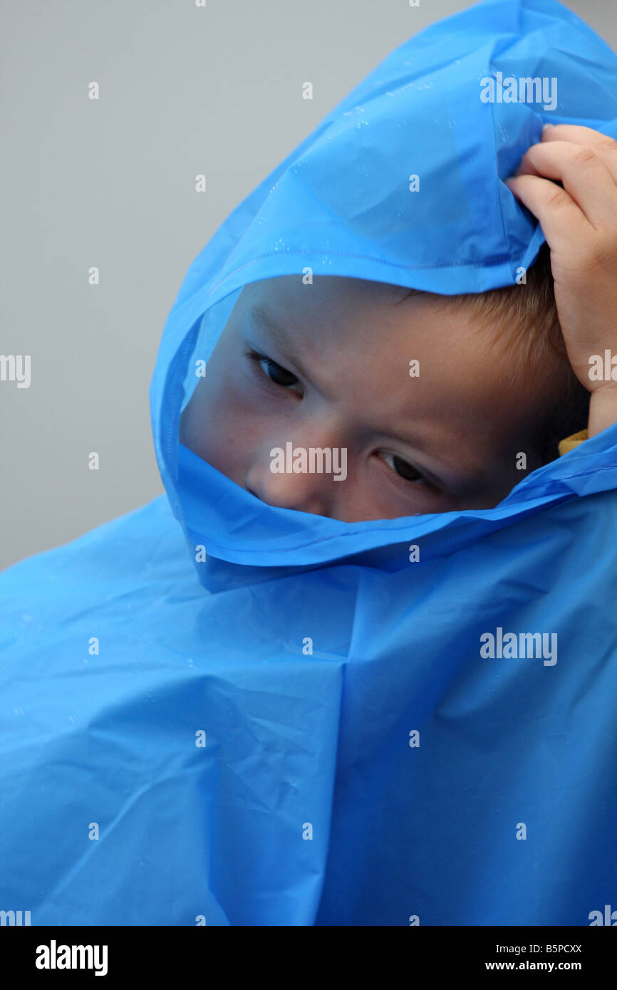 Ein kleines Kind mit einem blauen Regenponcho oder Jacke zu kämpfen Stockfoto