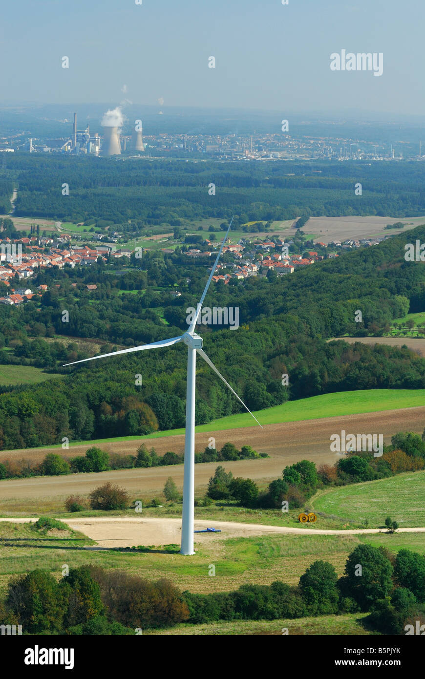 Luftaufnahme der Lichtmaschine und Propeller einer Windkraftanlage mit auf Hintergrund Kohle-Kraftwerke und französisches Dorf Stockfoto