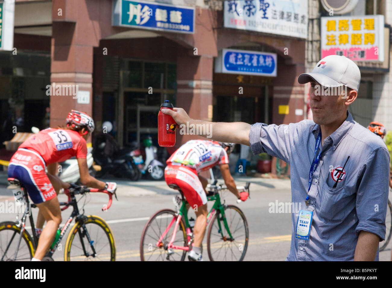 Radfahrer fahren vorbei an Assistent durchhalten Clif erschossen, Tour de Taiwan Stufe 1, Kaohsiung, Taiwan, ROC Stockfoto