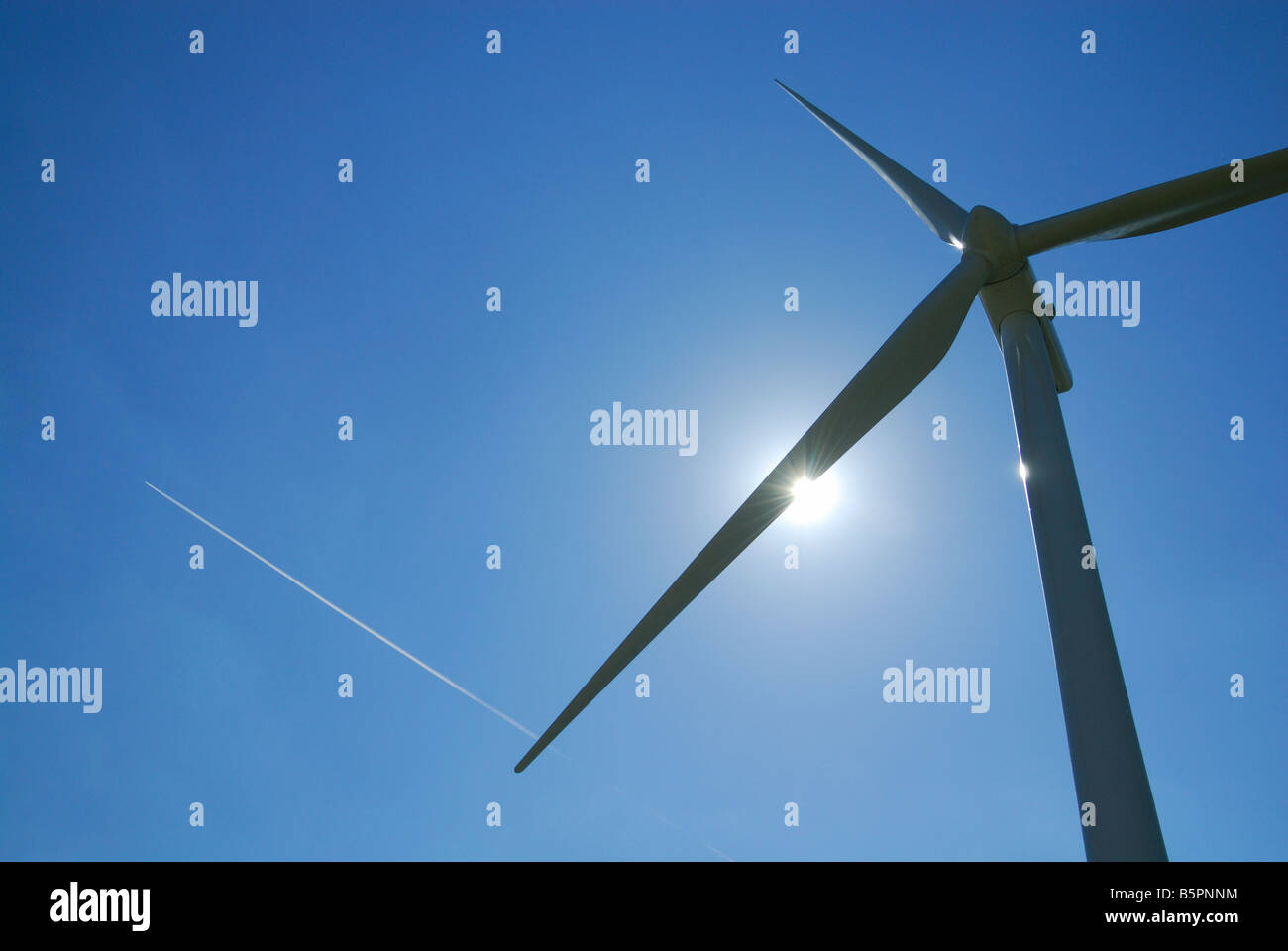 Eine horizontale Bild von einer Windturbine mit einer Rauch Spur von Verkehrsflugzeug in einen am blauen Himmel - Frankreich Stockfoto