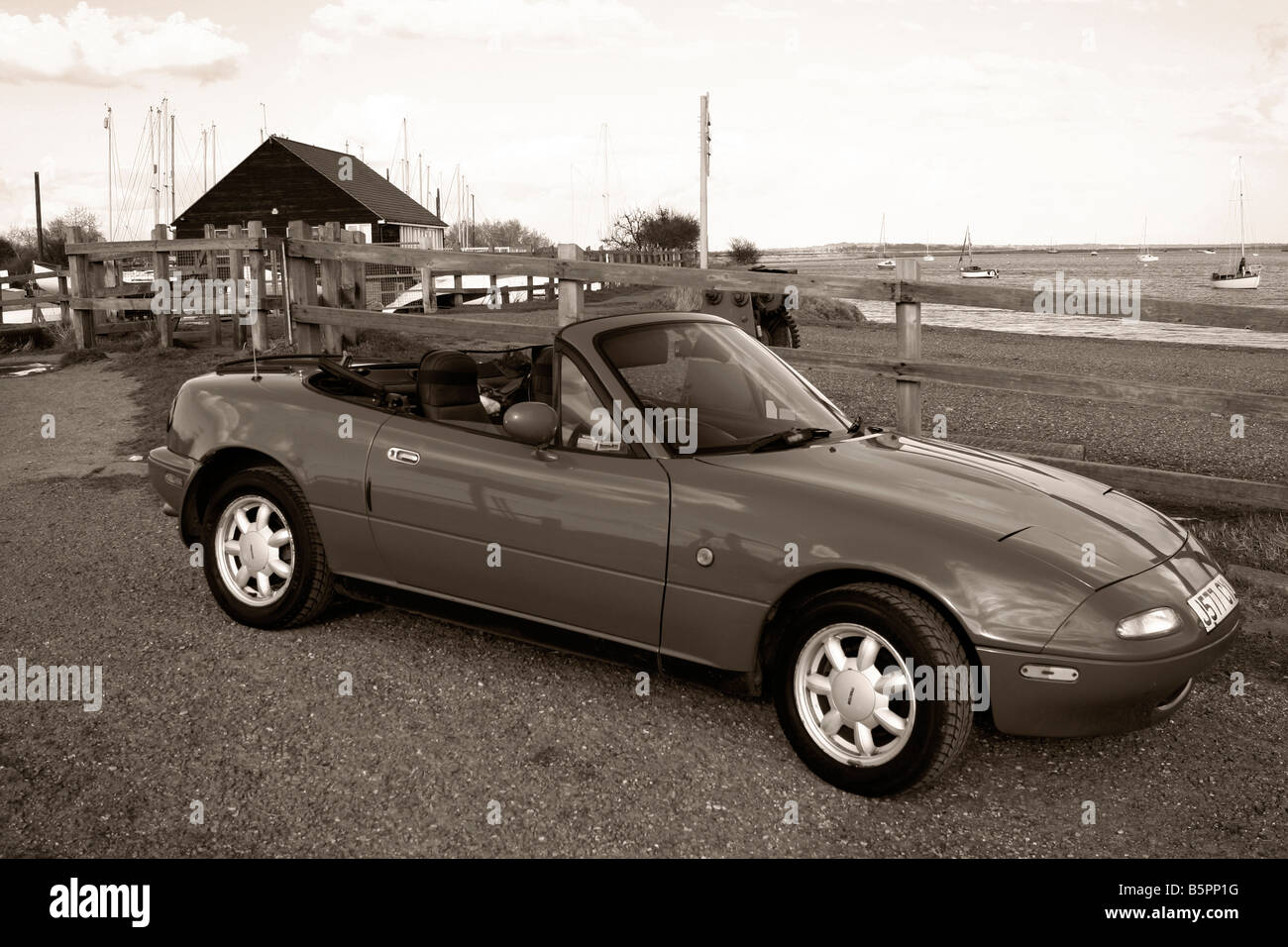 Mazda MX5 Mk1 2-Sitzer-Sportwagen mit Dach nach unten. Riverside-Einstellung. Monochromes Bild. Stockfoto