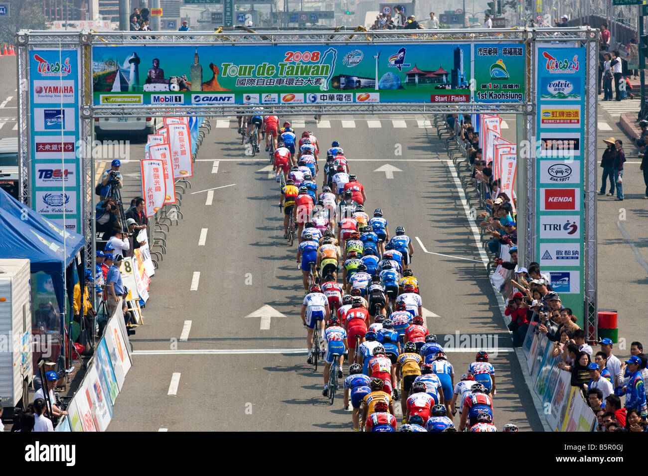 Radfahrer im Hauptfeld unter Start/Ziel-Barriere, Tour de Taiwan Stufe 1 Crtierium, Kaohsiung, Taiwan, ROC Stockfoto