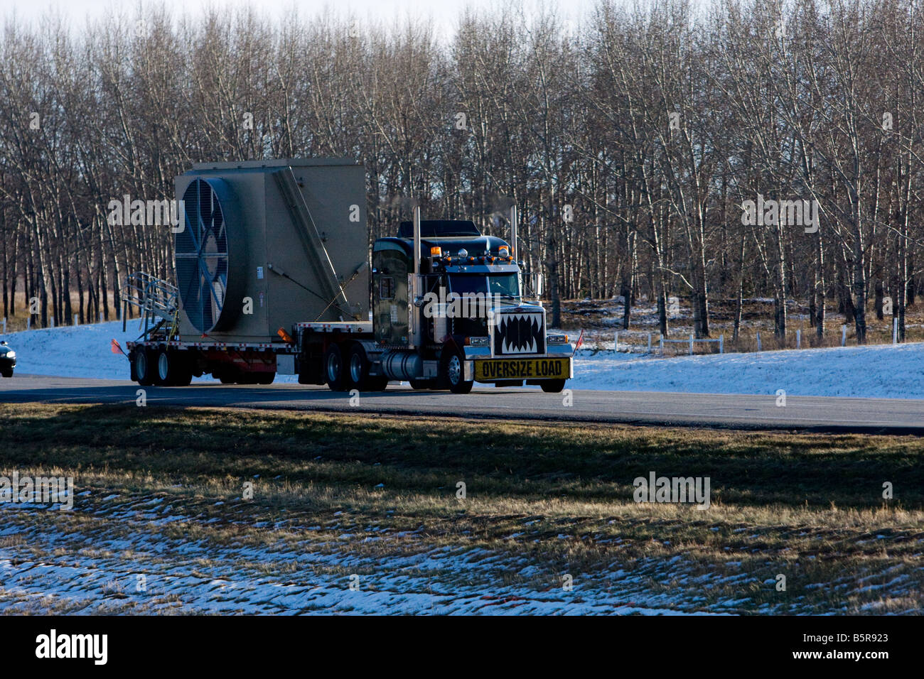 Semi-LKW fahren auf der Autobahn einem übergroßen Teil der Ausrüstung im Winter schleppen. Stockfoto